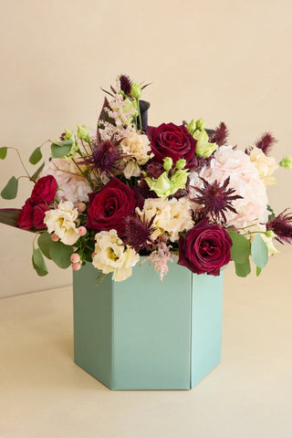 Hat box with a bouquet of flowers on a beige background